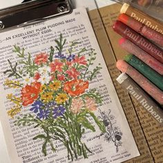 an old book with flowers on it next to some crayons