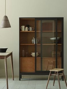 a wooden table sitting next to a glass door cabinet