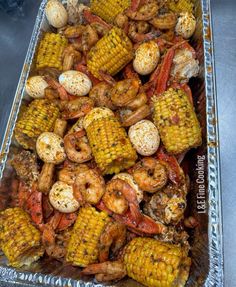 grilled shrimp and corn on the cob in a tin foil container, ready to be served