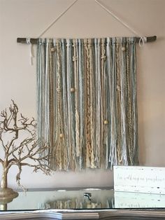 a wall hanging made out of yarn and rope with a bonsai tree in the background