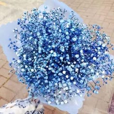 a bouquet of blue flowers sitting on top of a sidewalk