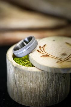 a wooden box with a ring on it and moss growing in the bottom, sitting on a table