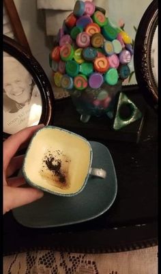 a person holding a cup with some food in it on a table next to a mirror