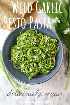 a bowl filled with pesto pasta and topped with pine nuts