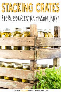 a wooden crate filled with mason jars sitting on top of a green plant next to a sign