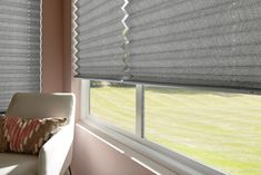 a living room with two large windows covered in gray roman blind shades and a white couch