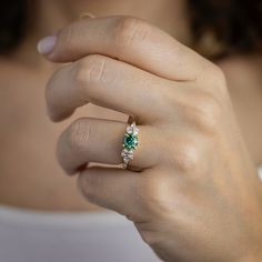 a woman's hand with a diamond and emerald ring