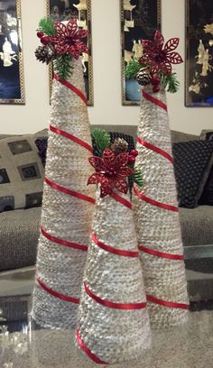 two white christmas trees with red bows and pine cones on them sitting on a table