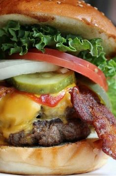 a bacon cheeseburger with lettuce, tomato and pickles on it