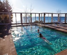 two people are swimming in a pool on the deck