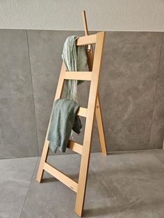 a wooden ladder with towels hanging from it's sides on the floor next to a wall