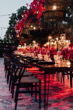 a long table with many candles and flowers on it is lit up by red lights