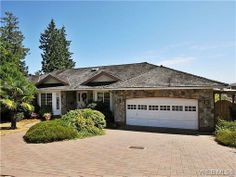 a house with two garages in front of it and trees on the other side