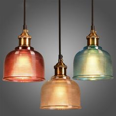 three different colored glass lights hanging from a ceiling fixture with one light on the other side