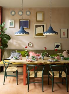 a dining room table with green chairs and pictures on the wall above it, along with other furniture