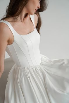 a woman is wearing a white dress and has her hand on the back of her shoulder