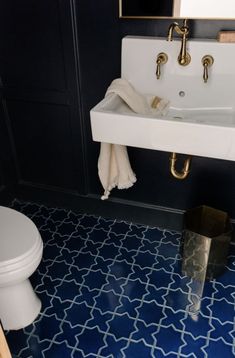 a white sink sitting next to a toilet in a bathroom under a mirror on the wall