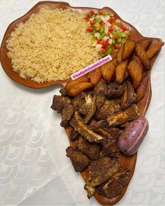 a wooden plate topped with rice and meat next to other food on top of a table