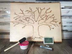 a wooden sign with a tree drawn on it next to some paint and brushes