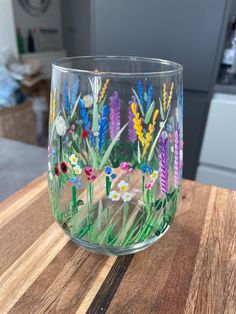 a glass with flowers painted on it sitting on a table