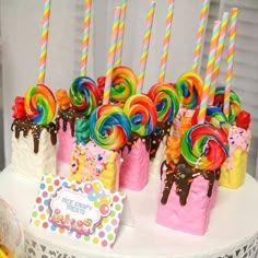 there are many colorful lollipops on the cake with candy sticks in them