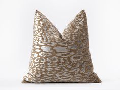 a gold and silver pillow on a white surface with an animal print pattern in the middle