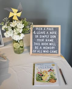 a table topped with a vase filled with flowers next to a sign