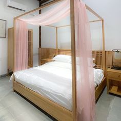 a bed with a pink canopy over it in a room that has white tile flooring and walls