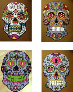 four different colored sugar skulls sitting on top of a wooden floor next to each other