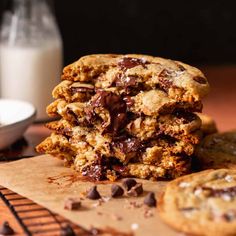 two chocolate chip cookies stacked on top of each other next to a glass of milk