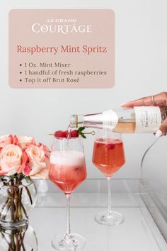 a person pouring champagne into two glasses with flowers in the background and a sign that says, raspberry mint spritz