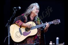 an older woman playing a guitar on stage