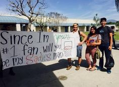 three people standing next to each other holding a sign