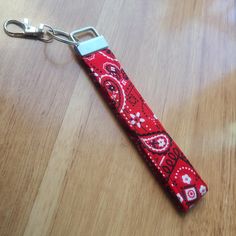 a red and white keychain with a pattern on it sitting on top of a wooden table