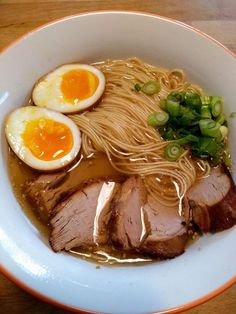 a bowl filled with ramen, meat and boiled eggs on top of it's sides