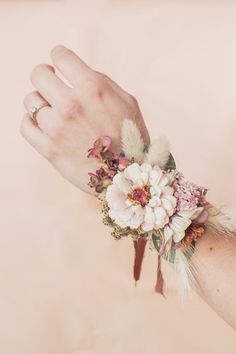 a woman's hand with a flower and feather wrist corsage on it