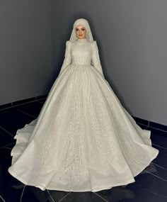 a woman in a white wedding dress standing next to a wall