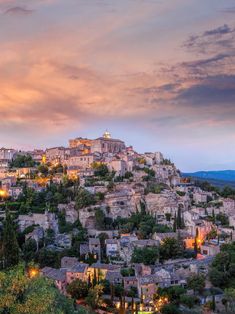 an old town on top of a hill at dusk with the sky in the background