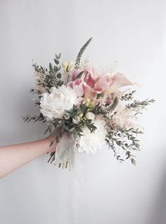 a bouquet of flowers is being held by someone's hand on a white background