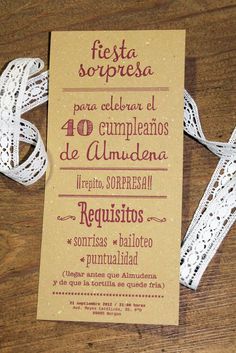 the wedding stationery is laid out on top of the wooden table, with ribbon tied around it