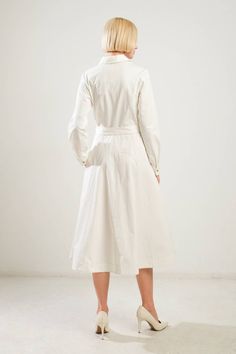 A solid woven midi dress featuring shirt collar, button down, long sleeve, self belt, side pockets and full skirt Details: Self : 100% Cotton Size & Fit - Model is 5`8" And Wearing Size Small- Measurements Taken From Size Small- Approx. Length: 47" Classic White Shirt Dress For Work, Spring Shirt Dress With Spread Collar, Elegant Cotton Shirt Dress With Belted Cuffs, Cotton Dresses With Belted Cuffs, Long Sleeve Midi Dress With Belted Cuffs For Daywear, Classic Long Sleeve Dress With Tie Waist, Classic White Shirt Dress For Fall, White Collared Shirt Dress For Work, White Elegant Shirt Dress With Tie Waist