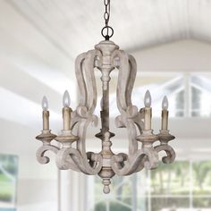 a chandelier hanging from the ceiling in a room with white walls and windows