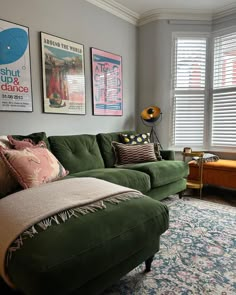 a living room with green couches and pictures on the wall above it's windows