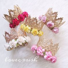 three crowns with flowers on them sitting on a white furnishing surface, one has gold wings and the other has pink roses