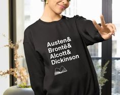 a woman wearing a black sweatshirt with the words austen and bronto & alcott & dickinson on it