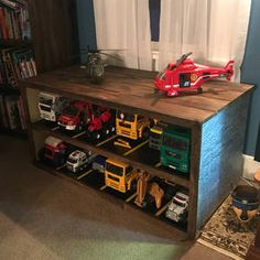 a toy helicopter is sitting on top of a book shelf with cars and trucks in it