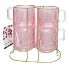 two pink glass mugs sitting on top of a metal stand