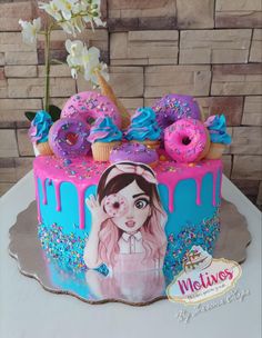 a pink and blue decorated cake with donuts on the top that have sprinkles