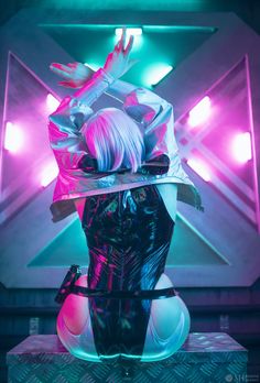 a woman with white hair wearing a black and pink outfit sitting on top of a table