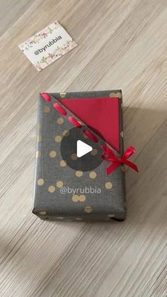 an open gift box with a red bow on it sitting on top of a wooden floor